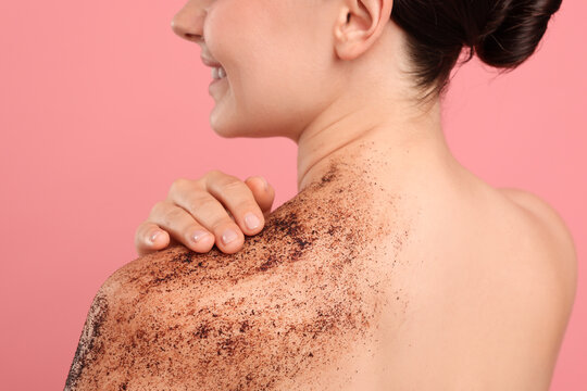 Smiling woman with body scrub on her shoulder against pink background