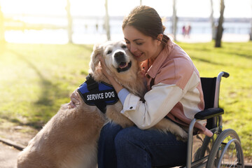 Woman in wheelchair hugging her service dog at park