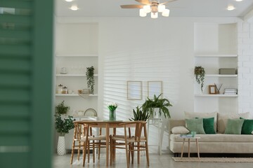 Comfortable sofa, table, chairs and green houseplants indoors. Interior design