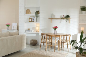 Stylish dining table with chairs and comfortable sofa in room. Interior design