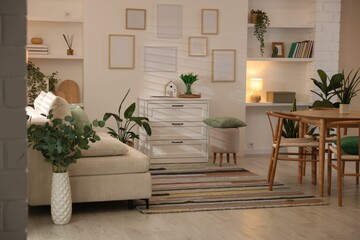 Stylish dining table with chairs and comfortable sofa in room. Interior design