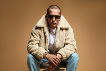 Fashionable portrait of handsome man in stylish outfit on brown background