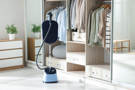 Modern upright steamer with stand near wardrobe indoors