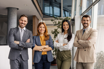 Corporate portrait of leaders standing at enterprise office with arms crossed and smiling at camera.