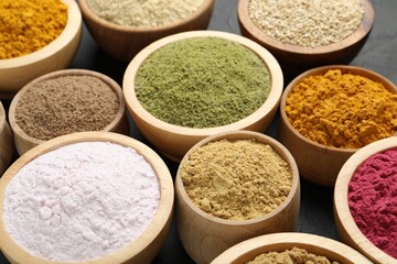 Different superfood powders in bowls on dark table, closeup
