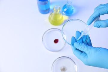 Scientist with Petri dishes and pipette on white background, top view. Space for text