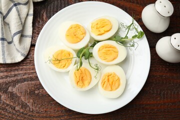 Boiled eggs and microgreens on wooden table, flat lay