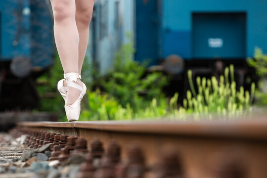 Eine Ballerina tanzt auf den Zehenspitzen auf einem Eisenbahngleis