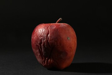 One rotten red apple on black background