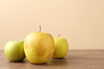 Many damaged green apples on wooden table. Space for text