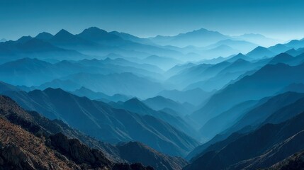 Obraz premium A bird's-eye view of distant mountains is shown in this image, with a clear blue sky visible from the mountain top