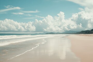 Sandy beach shore under bright blue sky with gentle waves and clear horizon