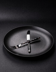 Empty plate with devices in the form of clock hands as a conceptual background for lunch time