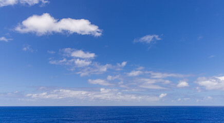 Fototapeta premium Serene Blue Sky with Clouds Overlooking a Vast Ocean Horizon