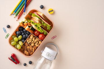 Prepared lunchbox featuring snacks, fruits, vegetables, nuts, and water, accompanied by school supplies