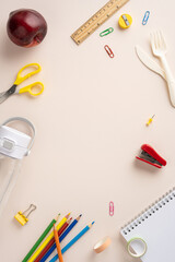 Vertical collection of school supplies, healthy snack, and utensils on a beige surface, organized neatly