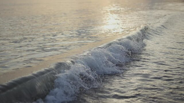 The ocean is calm and the water is still. The waves are small and gent