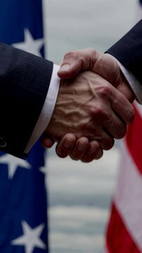 Handshake between two diplomats in front of USA flag. Two diplomats shake hands to signify an agreement in global relations. Diplomatic partnership and alliance sealed by handshake.