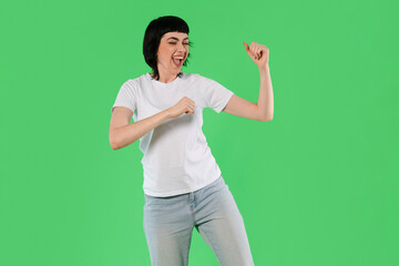 Energetic woman dancing joyfully against a vibrant green background during a fun indoor activity