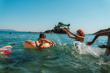 Young women are splashing and playing in the ocean on a sunny summer day, enjoying their vacation...
