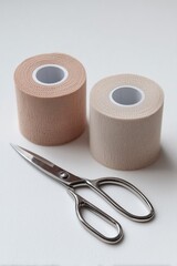 Ankle tape rolls and scissors on a white background with soft natural lighting for athletic support and injury prevention