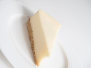 Traditional cheesecake on a white plate on a white background.