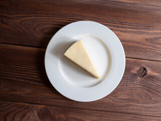 delicious cheesecake on a white plate. Wooden background, top view, flat lay