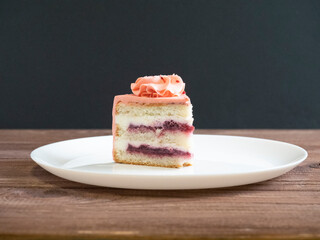 close-up of a piece of delicious layer cake on a white plate. Wooden table, dark background