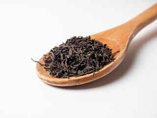 Close-up of a wooden spoon with loose Chinese tea. White background. Traditional tea from China.