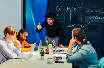 Business coach pointing finger while explaining growth strategies to employees