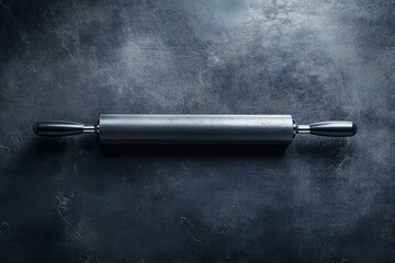 A dark gray rolling pin rests on a dark textured surface, ready for baking.