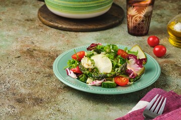Fresh vegetable salad with fried asparagus, arugula, cucumber and cherry tomatoes on a green plate on a green concrete background. Vegetable salads, vegan recipes. Seasonal vegetables.