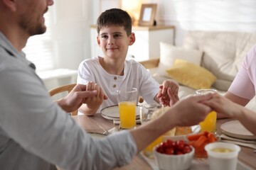 Family praying together before dinner at table indoors
