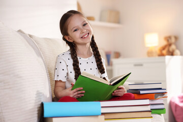 Cute girl with books on sofa at home