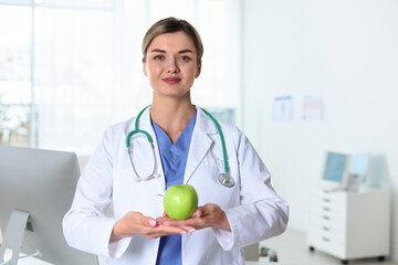 Nutritionist with green apple and stethoscope in clinic