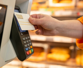 Buyer hand makes payment with bank card at POS terminal for purchases in supermarket close-up
