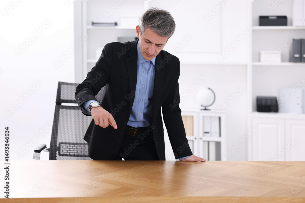 Poster man pointing at something on desk in office