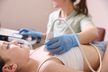 Sonographer conducting ultrasound examination of girl's heart in clinic, closeup