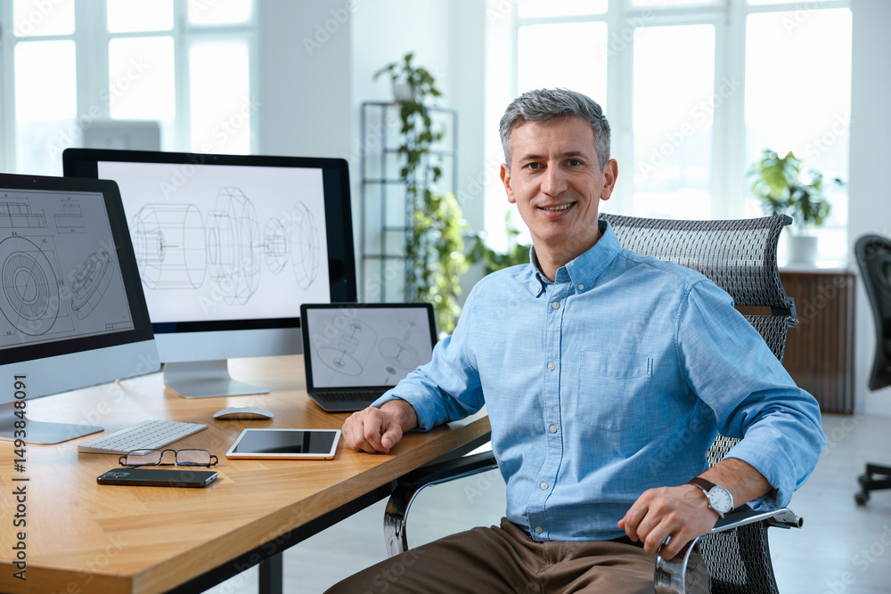 Poster portrait of smiling engineer at table with devices in office