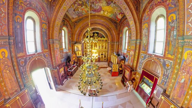 Belgrade, Serbia, Sept 1,2024: Sunlight is illuminating the interior of a serbian Orthodox Church of The Ascension in Belgrade. Showing the frescoes, iconostasis, and ornate chandelier. top view