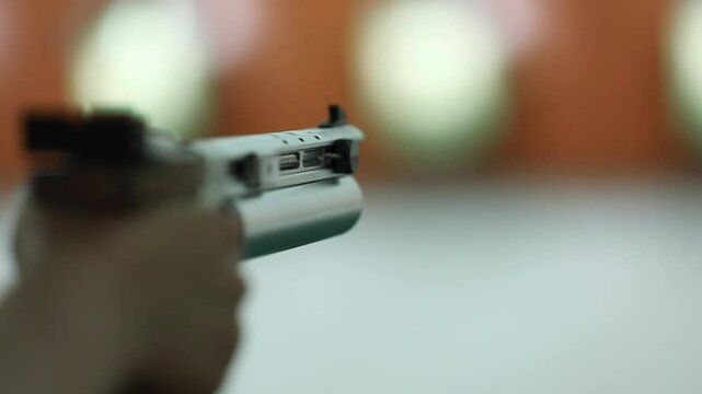 Close-up of a Sport air pistol firing, a puff of smoke visible from its silver barrel. Focus on precision against a blurred shooting range background. Perfect for marksmanship.