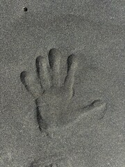 Handprint on the sand of gray volcanic beach in Tenerife, Canary Islands, Spain 