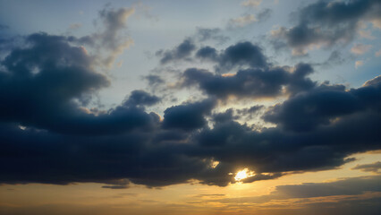 Obraz premium Sky filled with dark clouds during a vibrant sunset. Ideal for illustrating weather, nature, or evening scenes in creative projects.