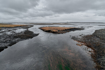 River flowing through desolate landscape under cloudy sky