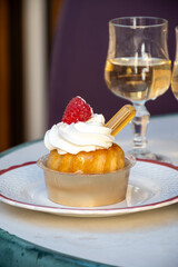 French cuisine, fresh baked baba au rum cake with chantilly cream, sweet dessert with rum and glasses of champagne wine close up