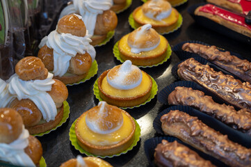 Variety of tasty French pastries, cakes, tarts, with cream and fruits on display in confectionery shop in France.