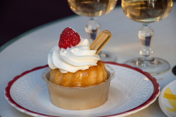 French cuisine, fresh baked baba au rum cake with chantilly cream, sweet dessert with rum and glasses of champagne wine close up