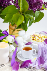 a cup of tea with cakes and a bouquet of flowers on the table