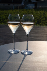 Glasses of white sparkling wine brut, grand reserve, champagne on green hilly vineyards in old wine making grand cru Ay-Champagne village in Vallee de la Marne, Champagne, France