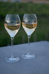 Glasses of white sparkling wine brut, grand reserve, champagne on green hilly vineyards in old wine making grand cru Ay-Champagne village in Vallee de la Marne, Champagne, France
